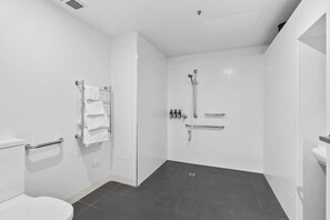 A modern bathroom with a toilet, a shower with a handheld showerhead, and a towel rack. - Gibson's Mill waterfront warehouse apartment - 103 (Hobart)