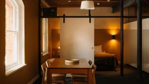 Una habitación acogedora con techo de madera, una mesa de comedor con sillas, un sofá con cojines y una cama con cabecera.