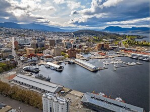 Une vue aérienne d’une ville avec un port de plaisance, des bâtiments et des montagnes en arrière-plan.