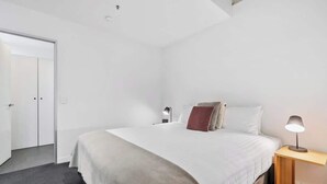 A modern bedroom with a large bed, a bedside table with a lamp, and a wardrobe. - Gibson's Mill 1 Bedroom Warehouse Apartment with Atrium
View - 204 (Hobart)