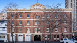 A historic red brick building with a sign reading "Gibson's City Flour Mills." - Gibson's Mill 1 Bedroom Warehouse Apartment with Atrium
View - 204 (Hobart)