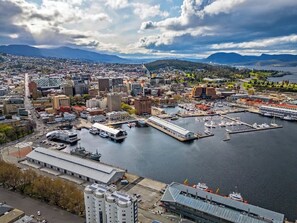 Panoramic city views of a bustling marina with rolling hills and distant mountains.