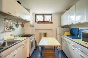 Kitchen with central island, white cabinetry, and tiled backsplash.