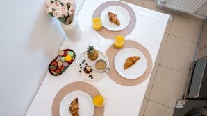 Una mesa de desayuno con croissants, fruta, jugo y una piña.