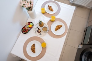 Una mesa de desayuno con croissants, fruta, jugo y una piña.