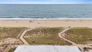A beach with a sandy shore, a wooden boardwalk, and a fenced area with vegetation.