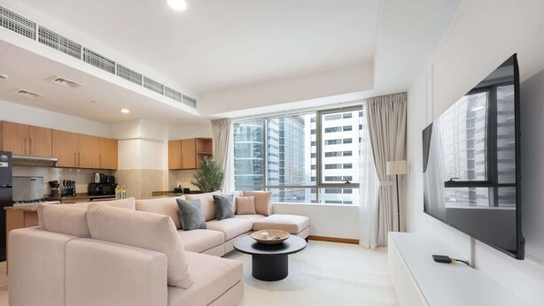 Un salon moderne avec un canapé beige, une table basse et un téléviseur à écran plat.