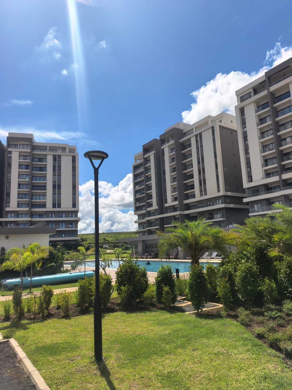 A residential building with multiple floors, a swimming pool, and surrounding greenery.