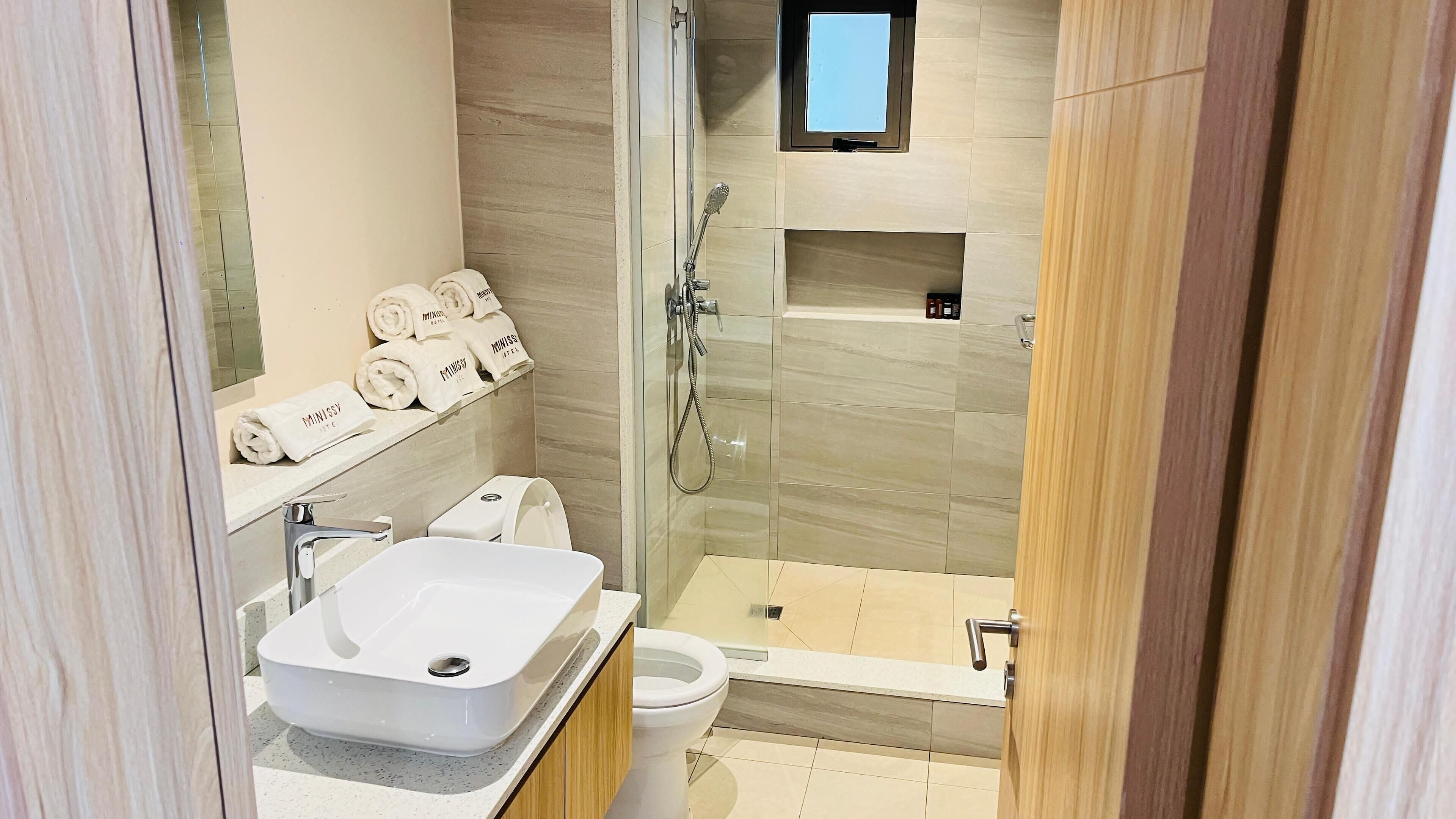 A modern bathroom with a glass-enclosed shower, a white sink, and a toilet.