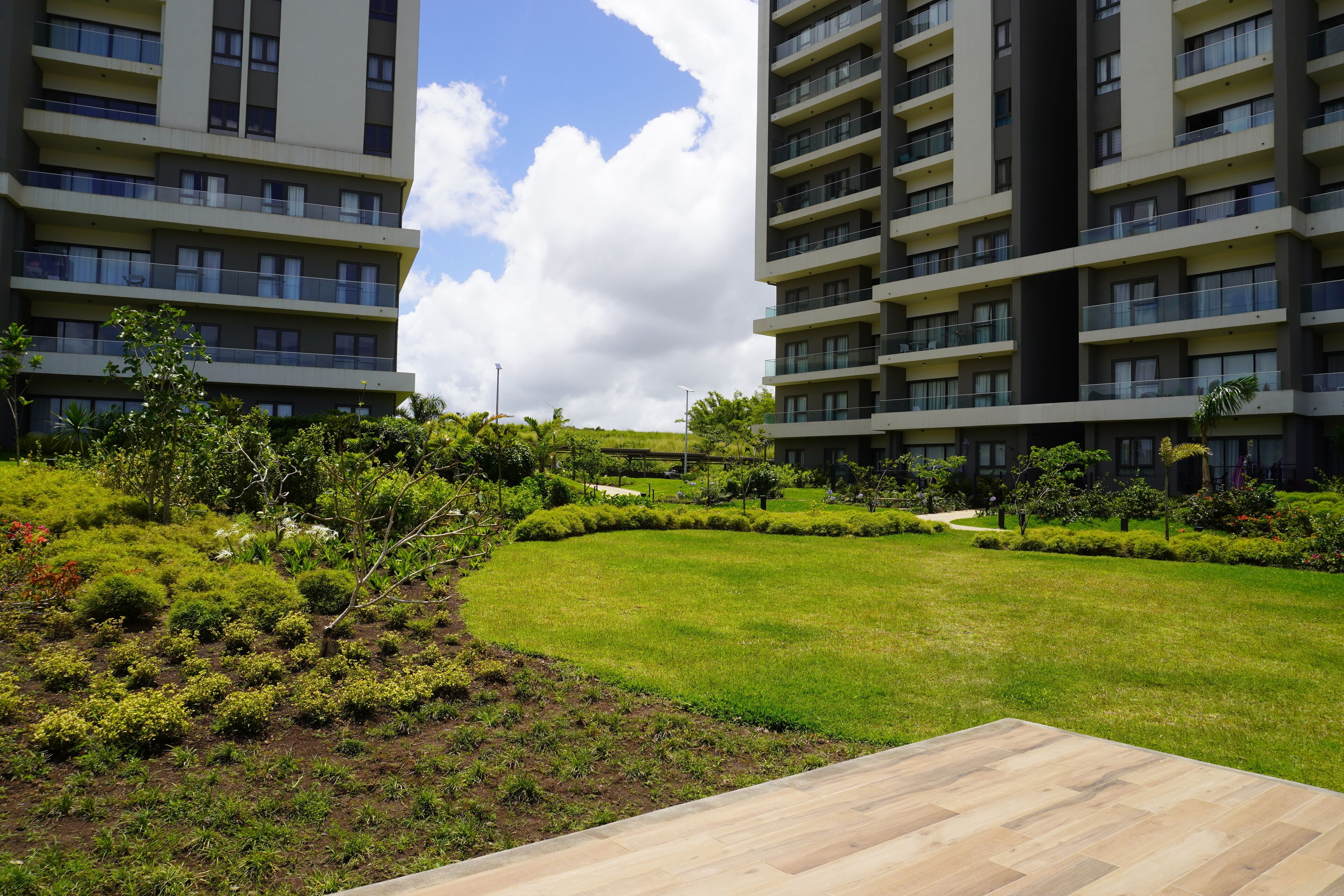 A modern apartment complex with multiple balconies, a well-maintained lawn, and a clear sky.