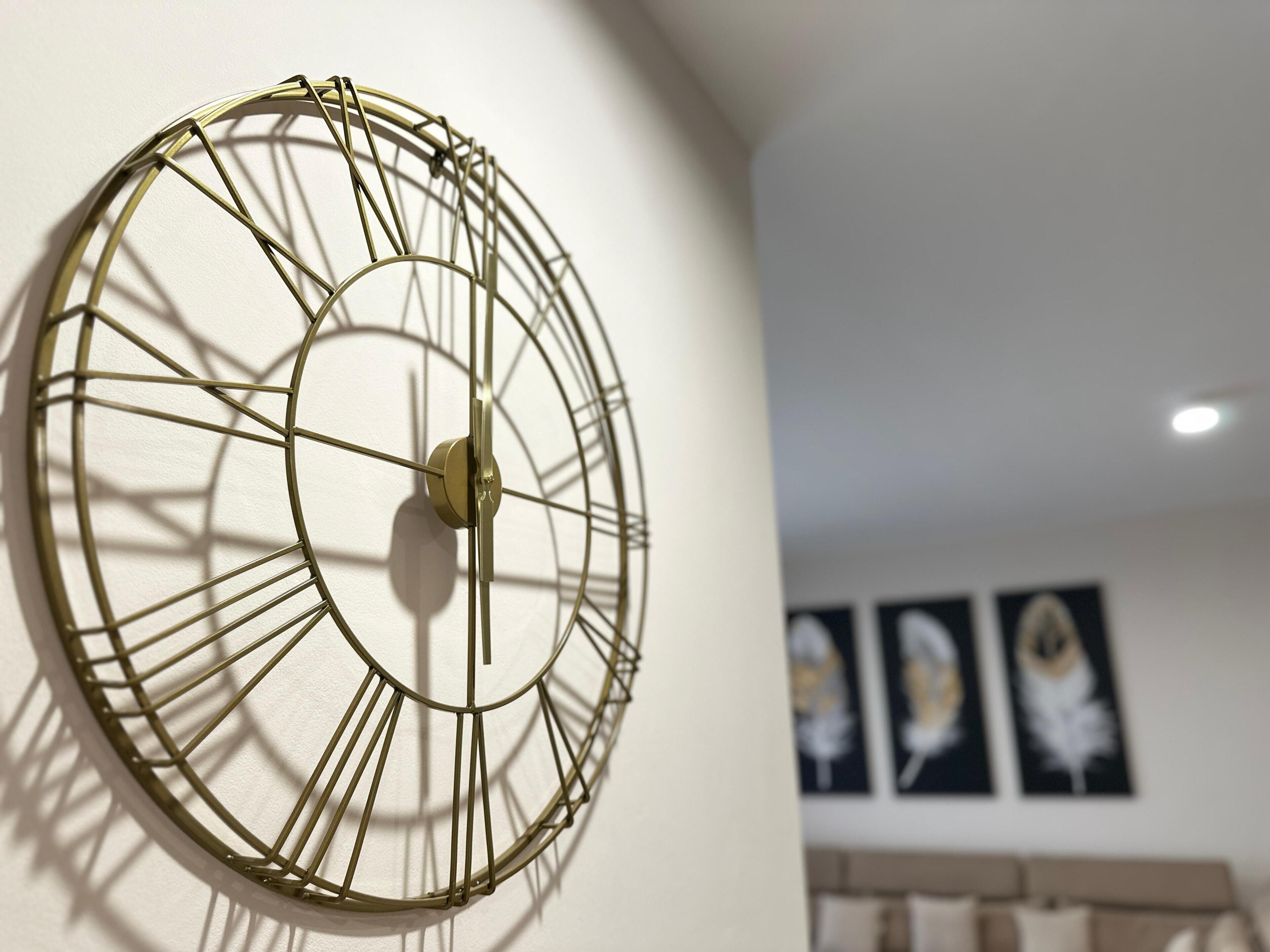 Um relógio fixado na parede, com design circular e eixo central.