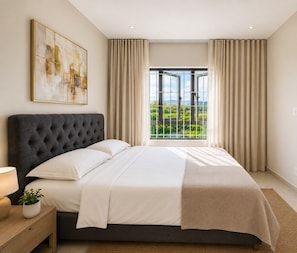 A modern bedroom with a large bed, a bedside table with a lamp, a potted plant, and a view of greenery through a window. - Minissy Suites (Moka)