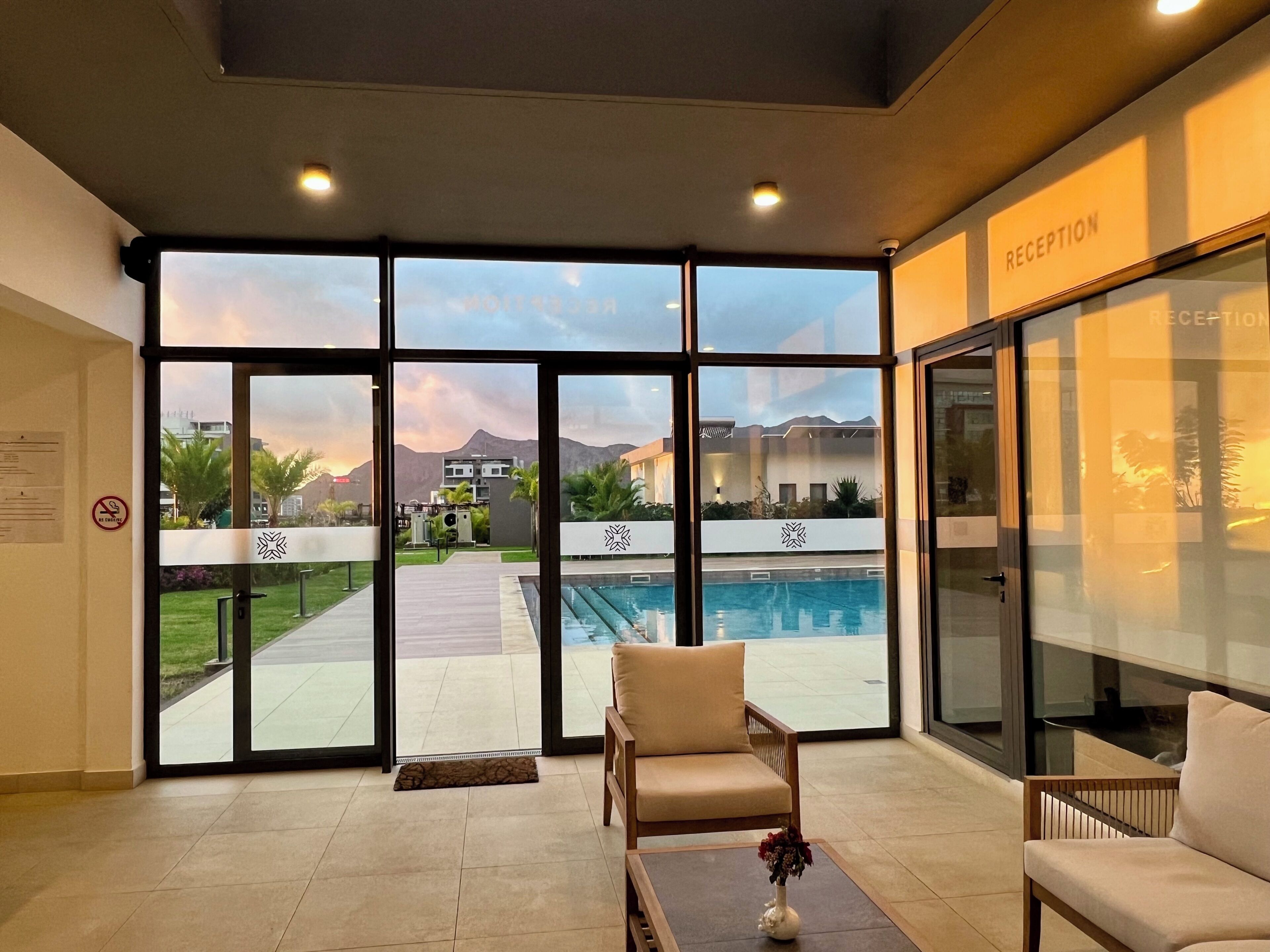 A reception area with a pool view, a reception desk, and a seating area with a vase of flowers.