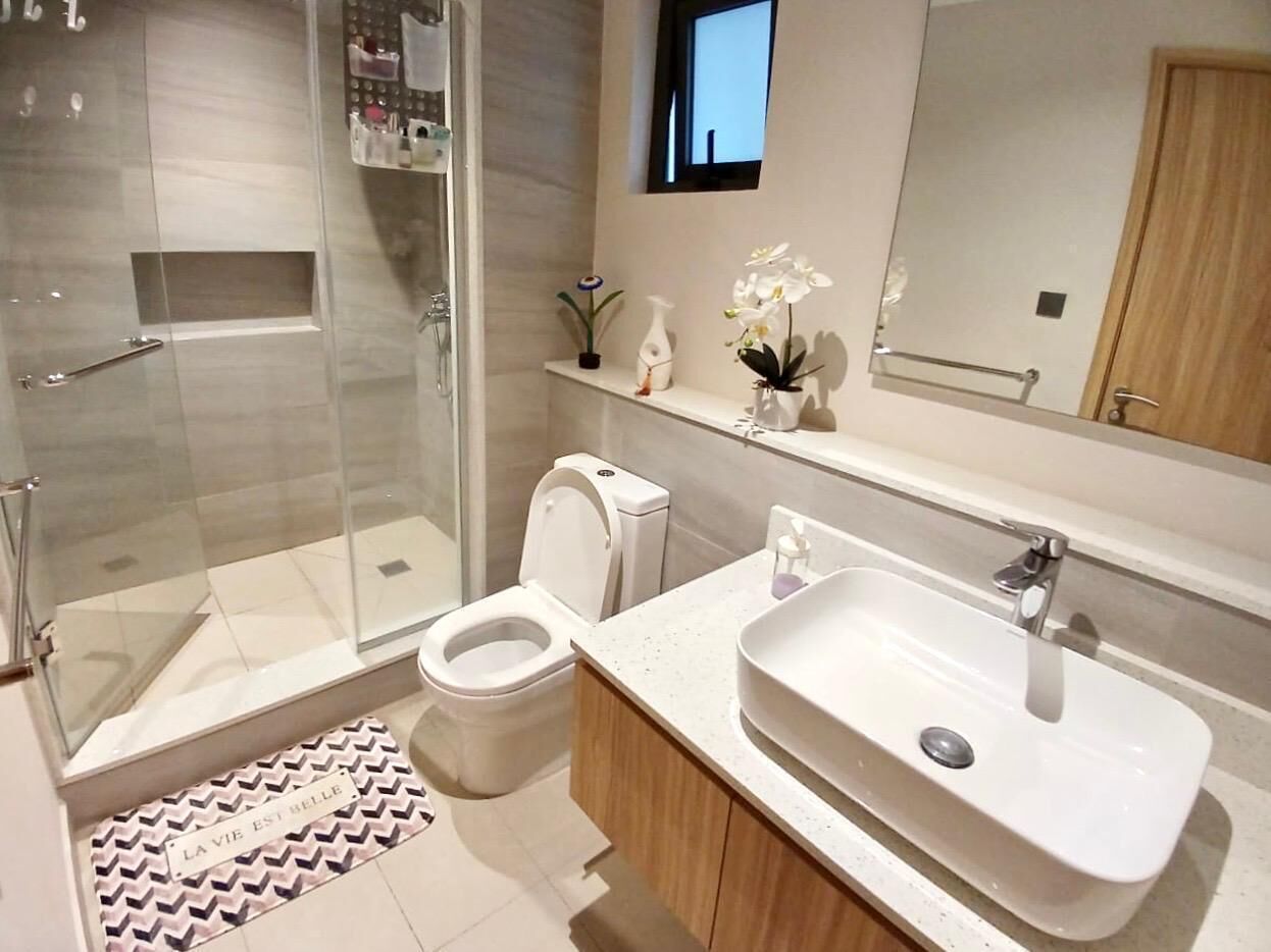 Et moderne badeværelse med et glasbrusekabine, toilet, vask og underskab.