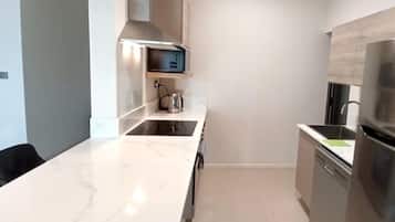 Una cocina moderna con encimera de mármol, electrodomésticos de acero inoxidable y horno empotrado.
