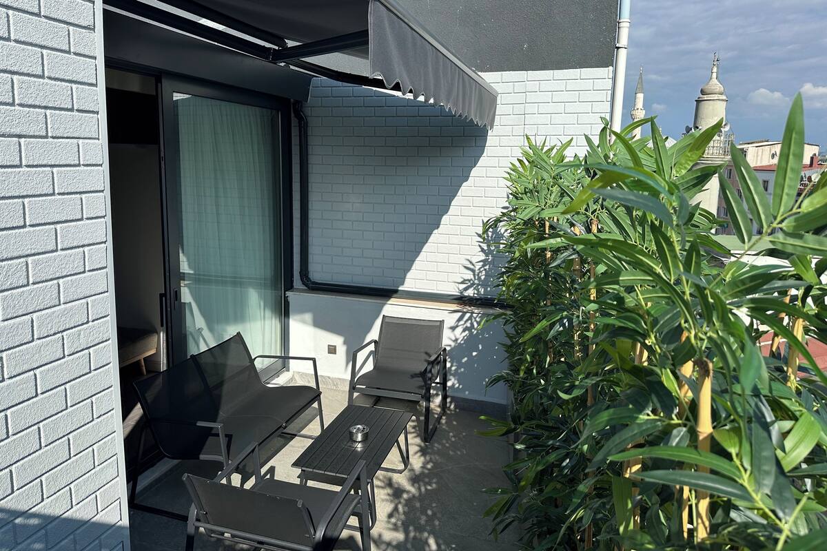 A patio with a table and chairs, a covered seating area, and a view of a building with a brick facade and a window.