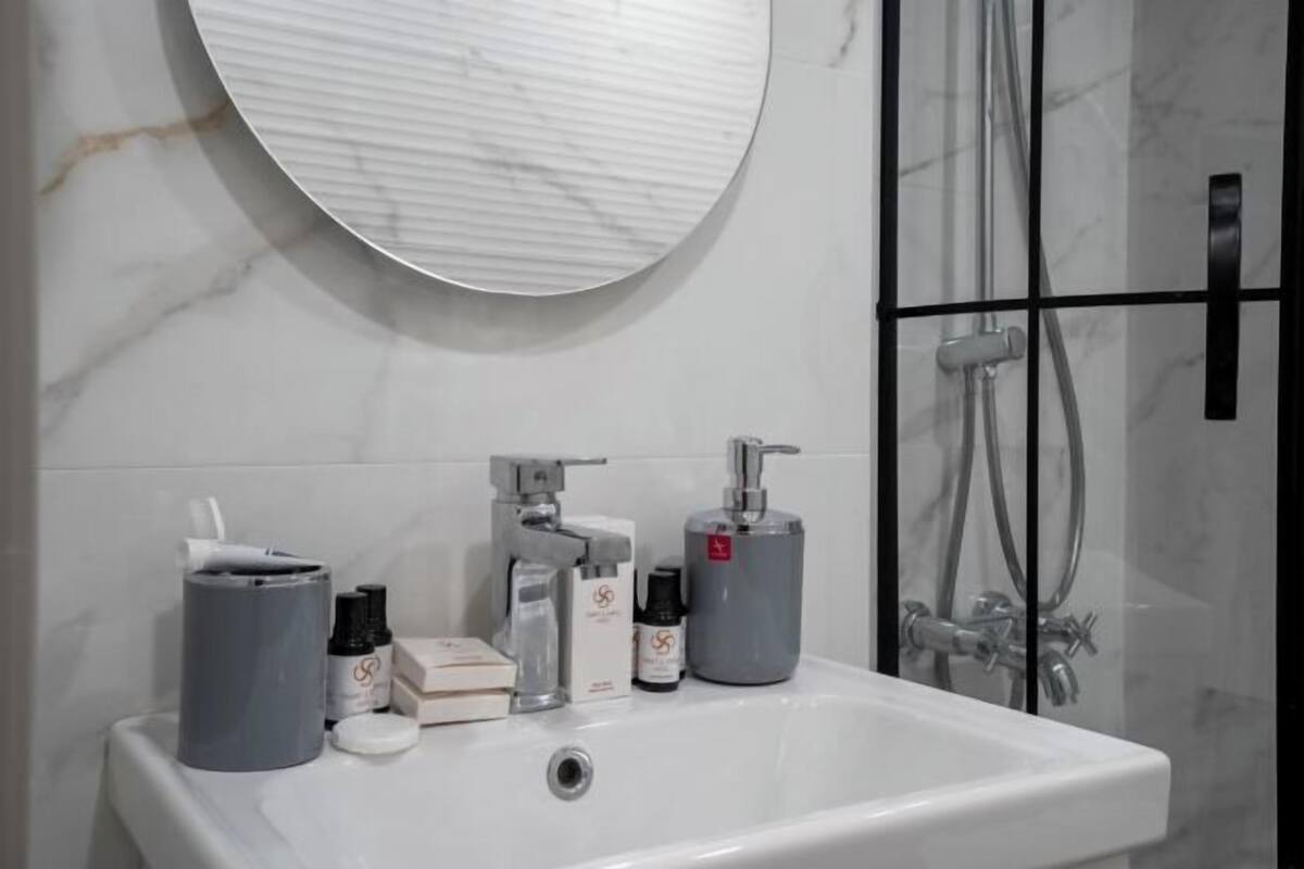 A bathroom with a white sink, a round mirror, and a shower area.