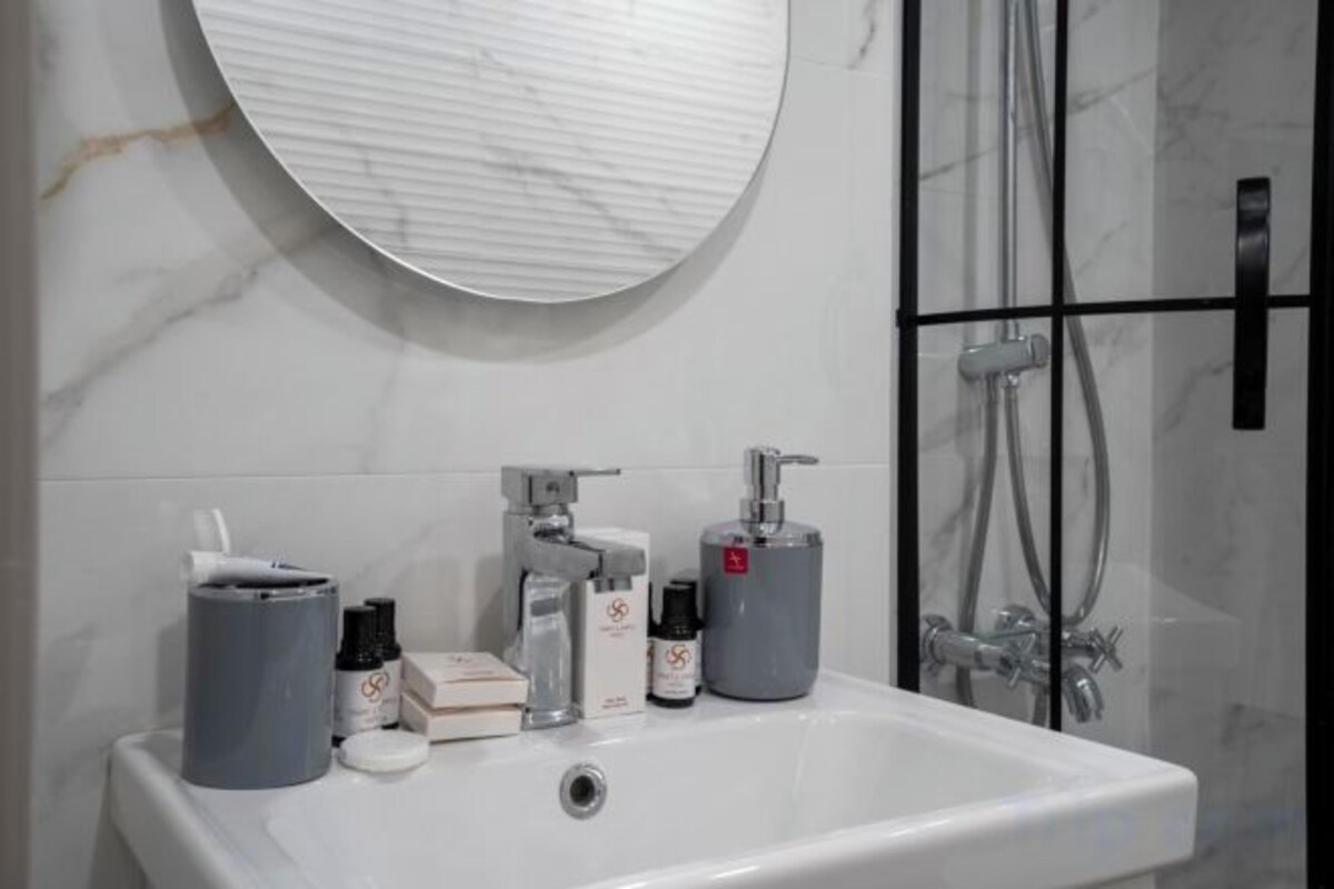 A bathroom with a white sink, a round mirror, and a shower area.
