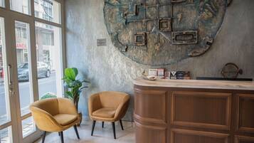 A reception area with a wooden counter, two armchairs, and a large decorative wall piece.