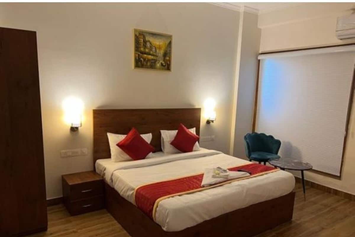 Una habitación de hotel con una cama de madera, dos lámparas de noche, una mesita pequeña y una silla.