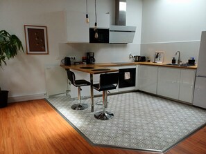 A modern kitchen with a wooden countertop, two bar stools, a coffee maker, and a stainless steel range hood. - Nice, comfortable one-bedroom apartment near Saint-Jean Station (Bordeaux)