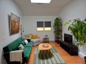 A modern living room with a green sofa, a grey sofa, a wooden coffee table, a TV stand, and a large plant. - Nice, comfortable one-bedroom apartment near Saint-Jean Station (Bordeaux)