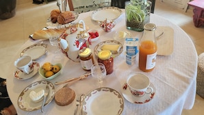 Ett frukostbord dukat med croissanter, bröd, sylt, honung, smör och en flaska apelsinjuice.