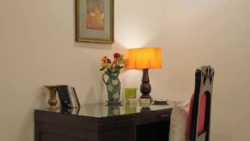 Un escriptori amb una làmpada, un ram de flors i un quadre al mur.