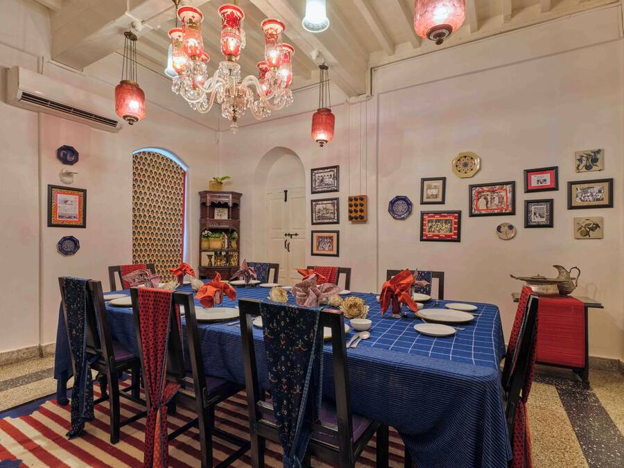 A dining area with a blue tablecloth, red and black chairs, and a chandelier.