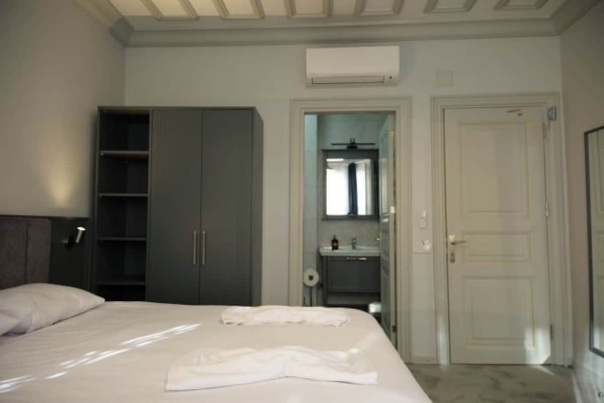 A bedroom with a bed, a wardrobe, a bathroom, and an air conditioning unit.