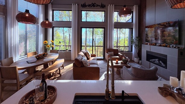 A spacious living room with a fireplace, large windows, and a dining area.