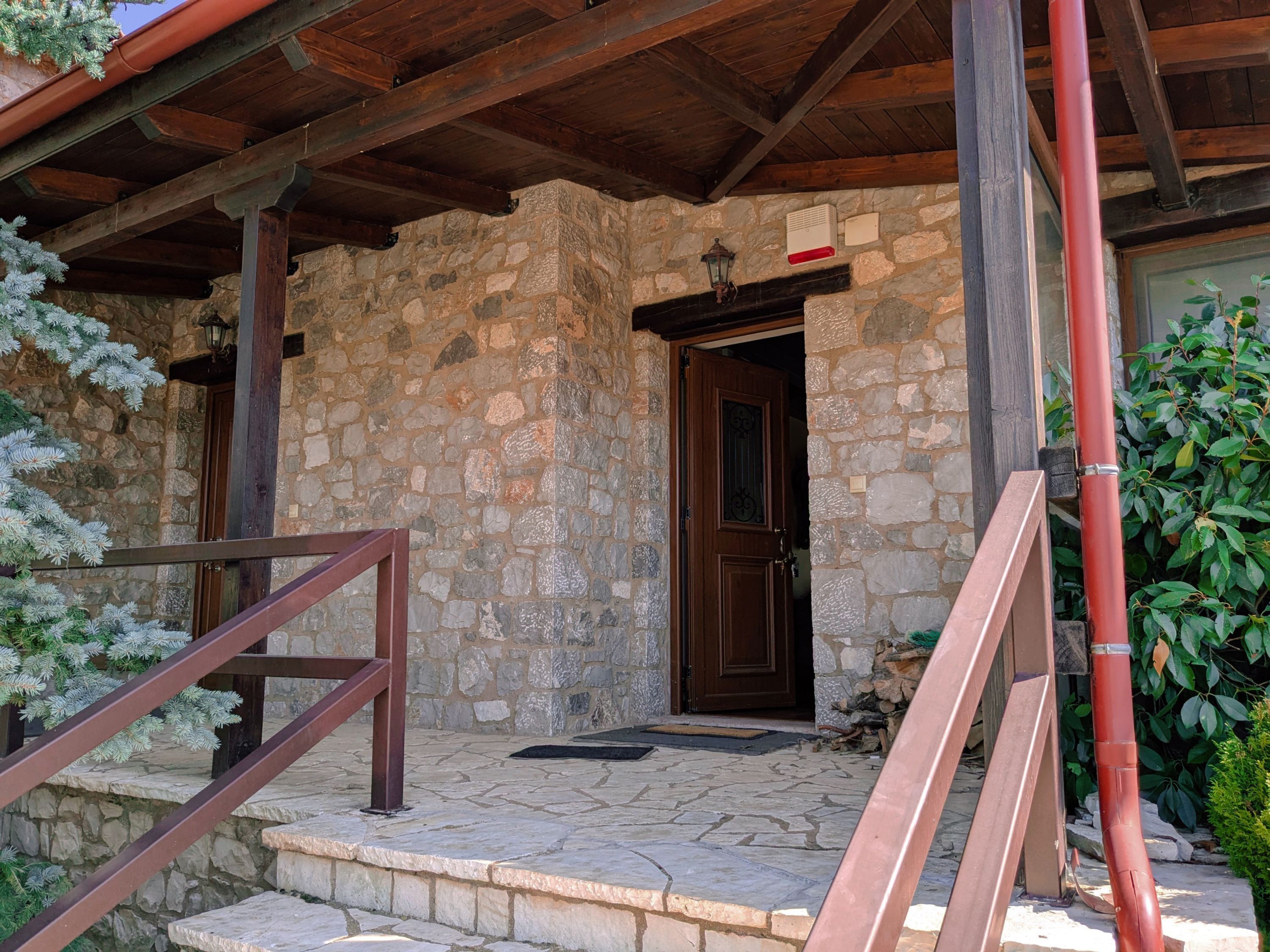 A stone building with a wooden porch and a brown door.