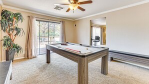 A pool table in a room with a ceiling fan, a potted plant, and a view through a window. - Pet-friendly Home w/ Game Room in Las Vegas! (Las Vegas)