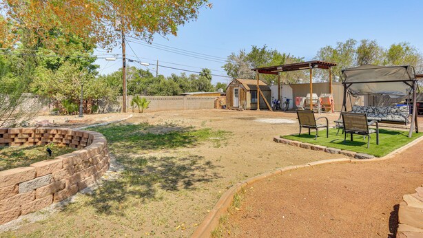 A fenced outdoor area with a picnic table and benches, a small building, and a tree. - Pet-friendly Home w/ Game Room in Las Vegas! (Las Vegas)