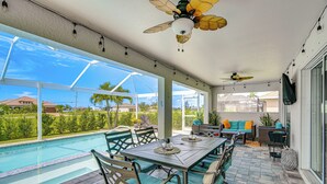 A covered outdoor area with a pool, seating, and a ceiling fan. - Cape Coral Home w/ Lanai ~ 7 Mi to Marina! (Cape Coral)