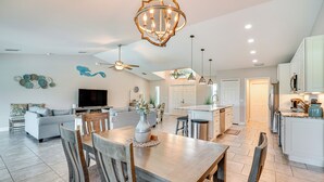 A spacious living area with a dining table, chairs, a sofa, and a TV. - Cape Coral Home w/ Lanai ~ 7 Mi to Marina! (Cape Coral)