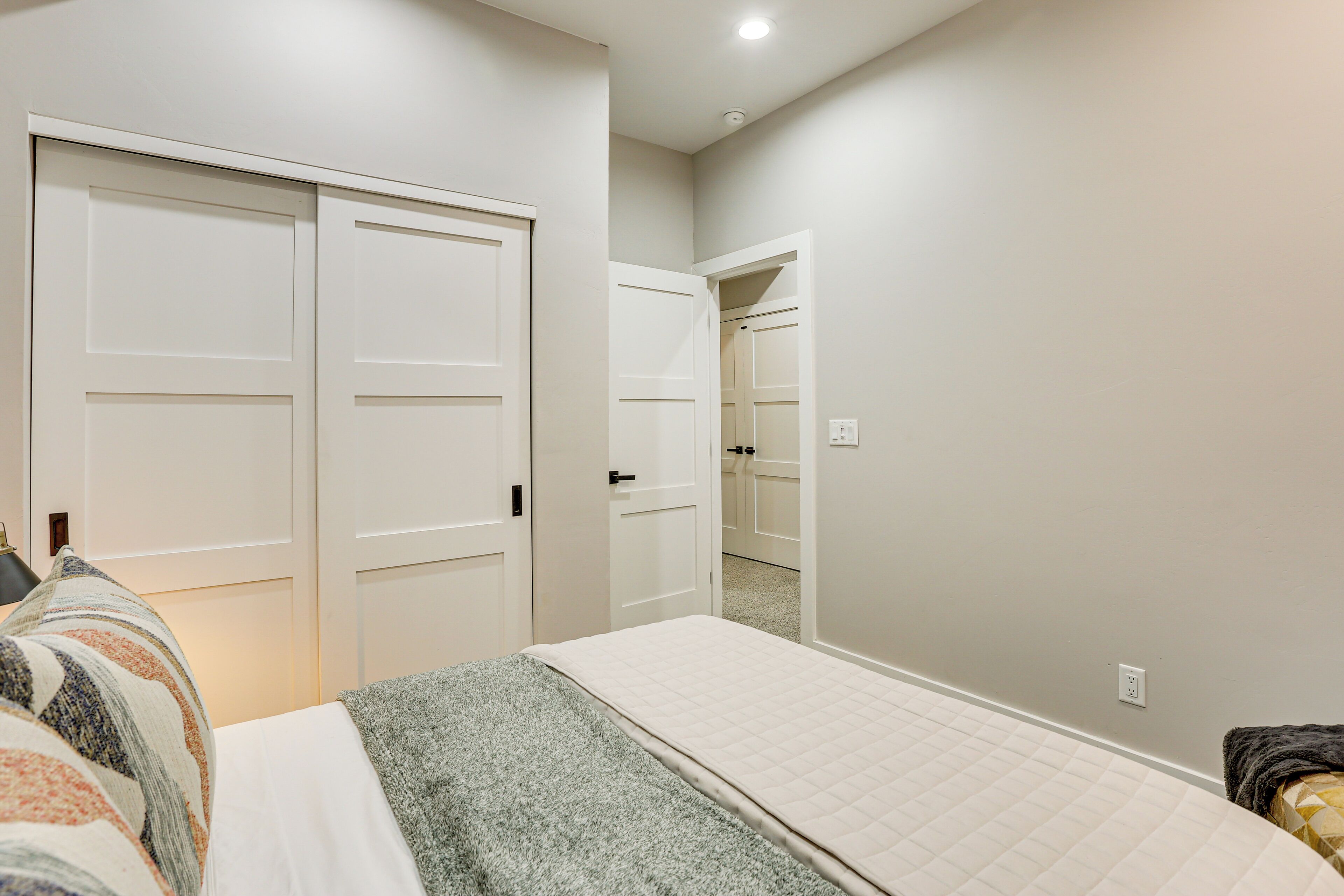 Un dormitorio con cama, armario y baño visible a través de una puerta abierta.