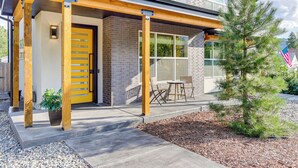 A modern building with a yellow door, wooden beams, and a small patio area with outdoor seating. - Hot Tub & Mtn-view Rooftop Deck: Golden Home (Golden)