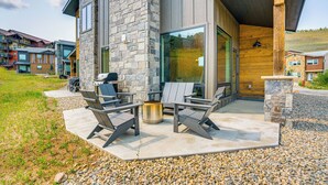 A modern house with a stone exterior, a patio with outdoor furniture, and a large window overlooking the landscape. - Mtn-view 'slopeside Chalet' in Granby Ranch! (Granby)
