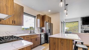 A modern kitchen with wooden cabinets, stainless steel appliances, and a large island. - Mtn-view 'slopeside Chalet' in Granby Ranch! (Granby)