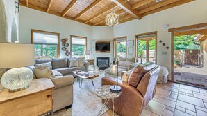 A spacious living room with a fireplace, wooden ceiling, and large windows. - Ruidoso Retreat w/ Hot Tub & Patio! (Ruidoso)