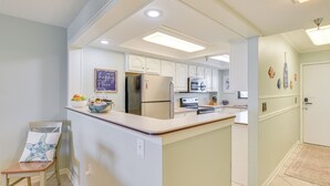 Una cocina con armarios blancos, un refrigerador, un microondas y un lavabo.