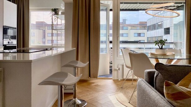 Une cuisine moderne avec un îlot central, un coin repas doté d’une table en verre et un canapé.