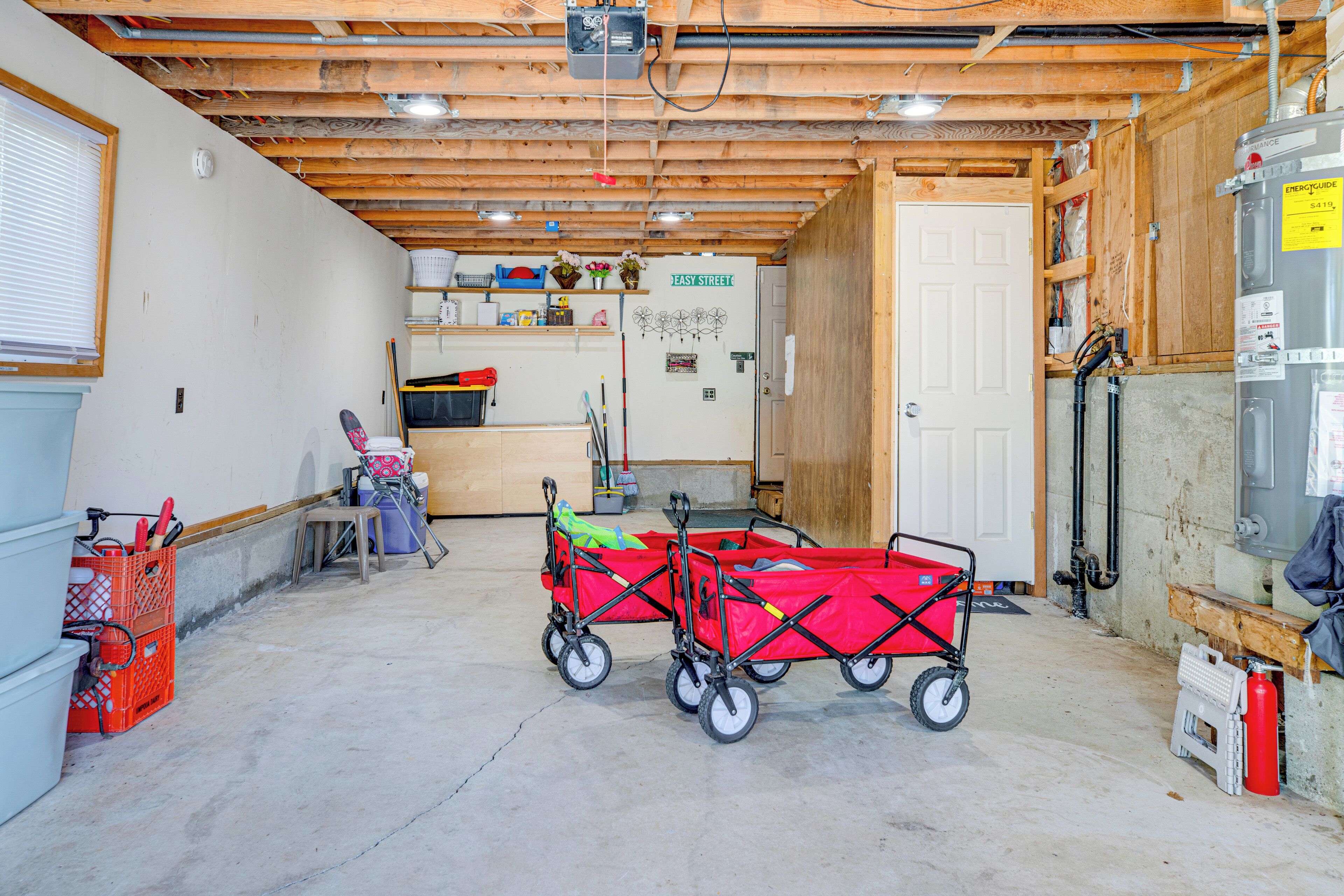Eine geräumige Garage mit Betonboden, Holzbalkendecke und einer weißen Tür mit der Aufschrift 'Jeasy Street'.
