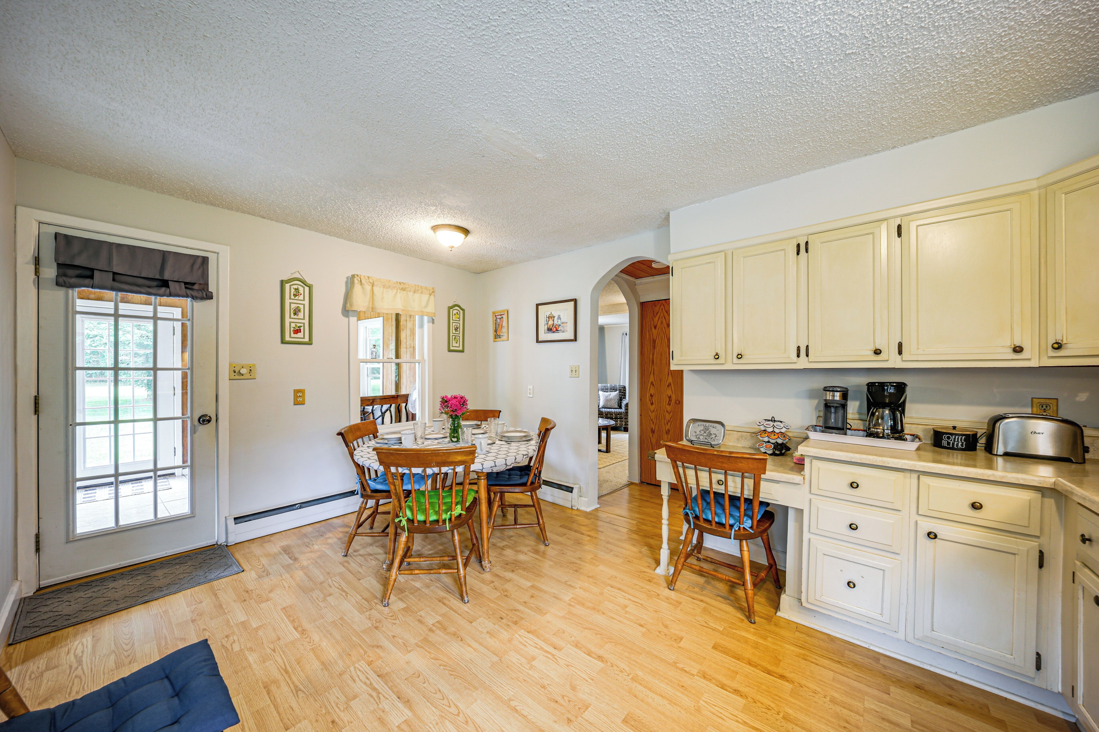A kitchen with wooden cabinets, a dining table with chairs, and a coffee maker.