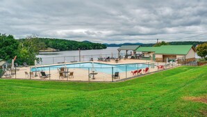 A swimming pool with lounge chairs and tables, surrounded by a fence, with a building in the background. - Home w/ Decks & River Access in Mt Gilead! (Mount Gilead)