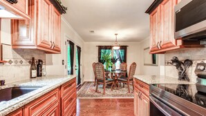 A kitchen with wooden cabinets, a granite countertop, a dining table with chairs, and a large stove. - Home w/ Decks & River Access in Mt Gilead! (Mount Gilead)
