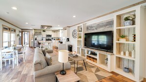 Un salon moderne avec un grand téléviseur, un canapé et un coin repas.