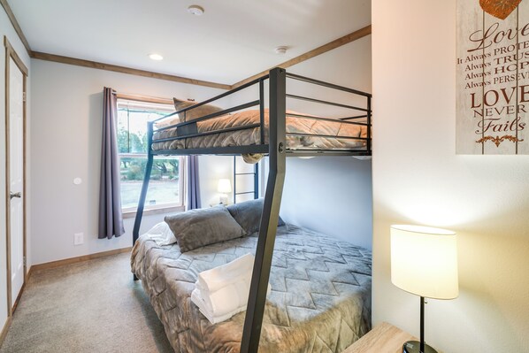 A bunk bed room with a window, a bedside table with a lamp, and a motivational quote on the wall.