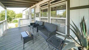 Une véranda aménagée avec des meubles en osier, notamment un canapé et des fauteuils, ainsi qu’une petite table.